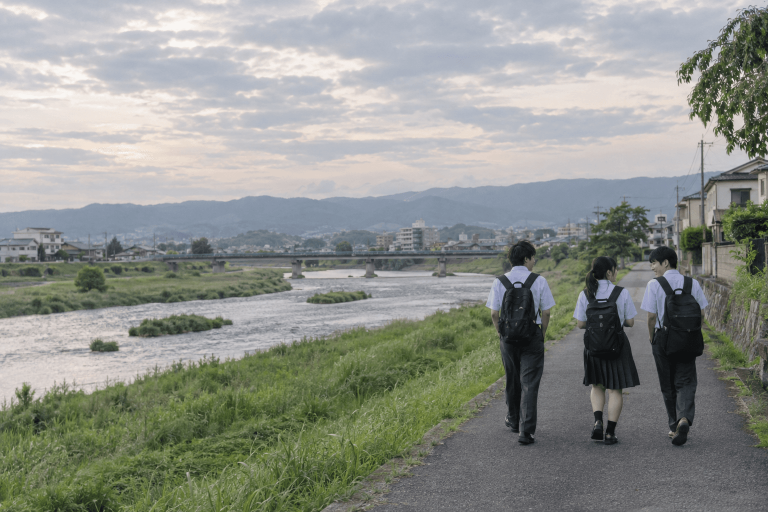 友達と話しながら川沿いの道を歩く高校生たちのイメージ